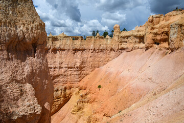 Looking out from the Queens Garden Trail at red rock hoodoo formations, in colors of pink, tan, and...