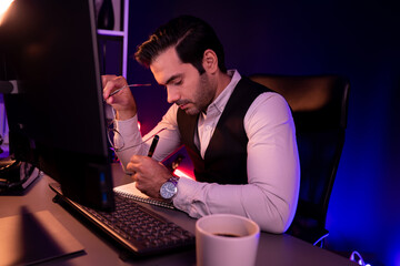 Stressful smart businessman writing memo market data on paper work report to analyze sales channel...