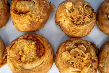 A tray of freshly baked onion swirl pastries with golden-brown crusts, close-up food display.