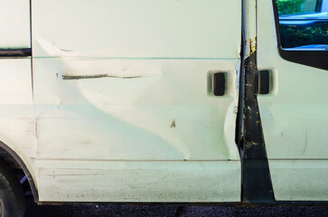 Close up dent damage on white minivan door vehicle repair problem