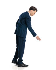 sexy young man in navy blue suit pointing finger down while walking
