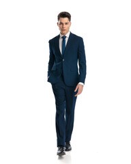 attractive businessman in navy blue suit looking at camera and stepping