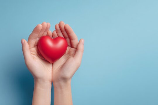 Hands Gently Holding Red Heart on Blue Background for Marketing Visuals