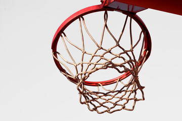 Basketball hoop, red ring and net, isolated on white background, underview. Sunny day, outdoors sport court
