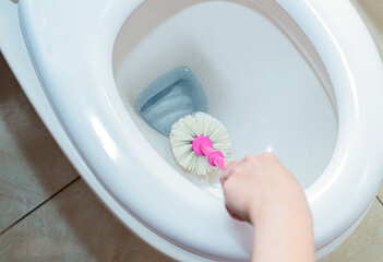 Scrubbing inside toilet with white brush