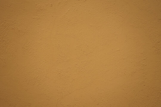 Textured background. Decorative plaster stucco concrete walls, external decoration of facade. Texture of yellow brown beige. Baked clay similar to cement or terracotta background. coating .Rustic wall