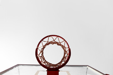 Basketball hoop, red ring and net, clear blue sky background, underview. Sunny day, outdoors sport court