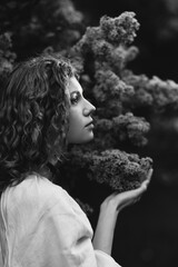 Young pretty caucasian woman in romantic outfit walking in blooming spring garden. Artistic outdoor photo of beautiful red-haired girl posing in fragrant lilac blossom.