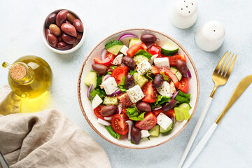 Greek salad with olives on white table. Fresh vegetables, cheese and olive oil. Flat lay