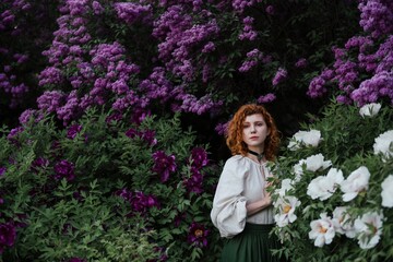 Young pretty caucasian woman in romantic outfit walking in blooming spring garden. Artistic outdoor photo of beautiful red-haired girl posing in fragrant lilac blossom.