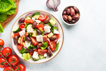 Greek salad with olives on white table. Fresh vegetables, cheese and olive oil. Top view with space for design.