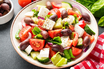 Greek salad in craft plate on black background. Vegan food, mediterranean diet. Close up.
