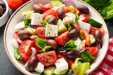 Greek salad in craft plate on black background. Vegan food, mediterranean diet. Close up.