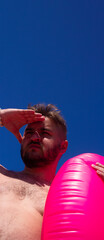 Vertical banner. Street photo. Bottom view. Fat white man with stubble, big belly, pink inflatable...