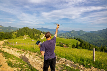 Man Launching Drone in Mountain Landscape. Person raising a drone into the air with remote control...