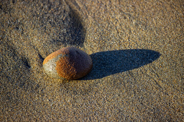 A single rock and its shadow reflect solitude, stillness, and mindful presence