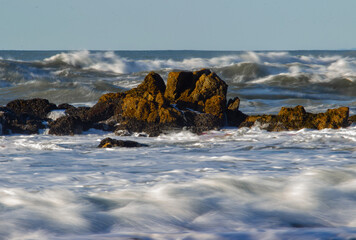 Crashing ocean waves over rocky shore reflect nature’s raw energy and shifting moods