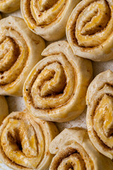 Making homemade cinnamon puff pastry buns. Raw dough rolls greased with egg yolk.