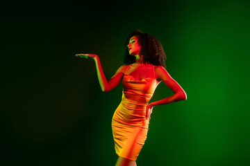 Stylish stunning woman in golden dress posing against vivid green gradient background with elegance