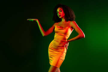 Elegant young woman in a stylish cocktail dress posing against a green and red gradient background