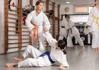 Assertive young girl applying throwing technique to her partner during judo classes