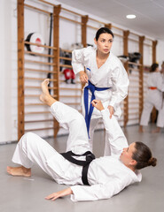 Assertive young girl applying throwing technique to her partner during judo classes
