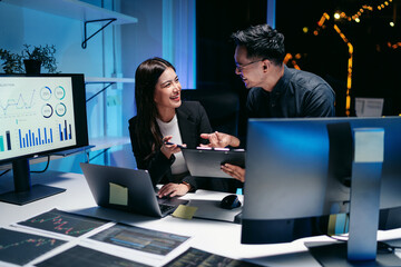 Adult business professionals analyzing market data and financial stocks late night in a modern...