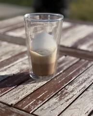 Cafe latte macchiato layered coffee in a see through glass coffee cup. The cup is on a wooden...