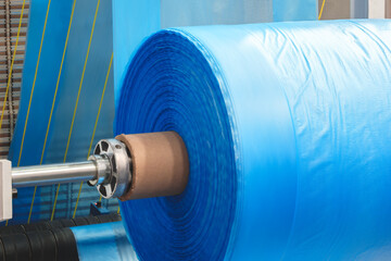 A machine with a roll of polyethylene plastic film on it. The machine is in a factory. industrial...