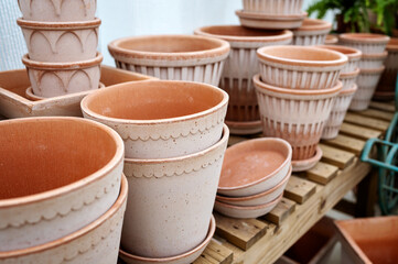 Various clay and ceramic flower pots in different shapes and textures arranged on outdoor wooden...