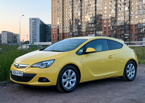 Bright yellow car Opel Astra J GTC in the city street. Motor sports car Opel Astra J GTC hot hatch in the city street. Opel Astra J GTC hatchback. Germany car. 