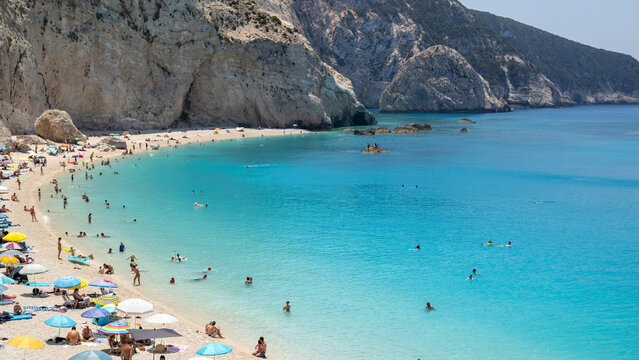 crowded beach turquoise water rocky cliffs