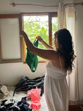 woman in her vacation accommodation, takes out her green one-piece swimsuit.