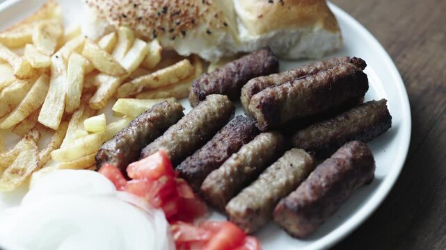 A balkan traditional meatball dish cevapi, cevapcici on wooden table in close-up	