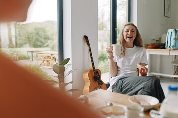 happy middle age woman enjoying healthy breakfast with coffee at home, promoting active wellness...
