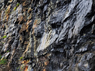 A rock wall with a lot of rust and cracks. The wall is made of stone and has a lot of texture....