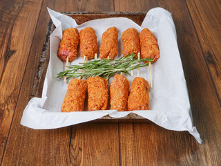 Fancy kebabs on wooden sticks and fresh rosemary fresh herb on cooking paper in a cooking tray on...