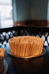 A close-up of wooden coffee stirrers placed in a round container on a table in a cozy cafe...