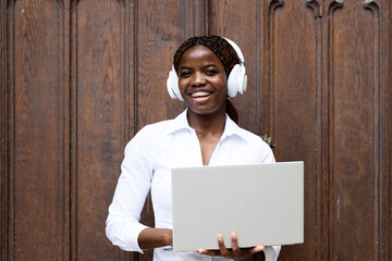 Portrait of happy female black freelancer working on laptop computer outdoors.