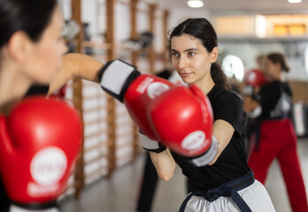 Sportive young girl training boxing in pair with his partner during sports classes