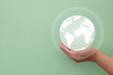 Hand holding a glowing world globe on a green background.Concept of sustainability, environmental conservation,SG, and climate change awareness with copy space.