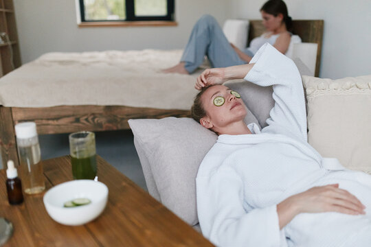 Relaxed middle age woman enjoying wellness care with cucumber slices on eyes at home, focused on health and relaxation for wellbeing and longevity.