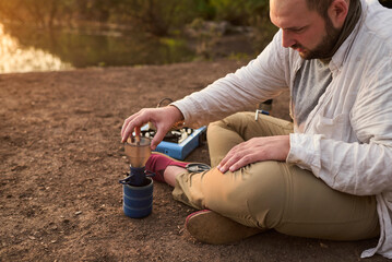 Coffee filtering process. Hispanic man making coffee for breakfast outdoors early in the morning by...