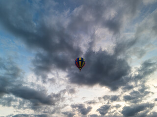 Colorful hot air balloon flying through cloudy sky