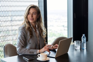 A professional businesswoman is actively engaged in her work at a chic and stylish office, where...