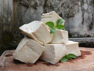 Close-Up of Tofu Cubes with Basil Leaves on Wooden Board 
