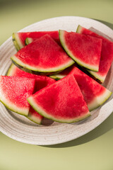 Slices of fresh watermelon fruit in a oval plate, green abstract background