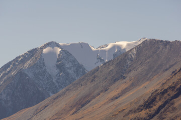 Majestic snow-capped mountains rise against a clear blue sky, showcasing rugged terrain and rocky...