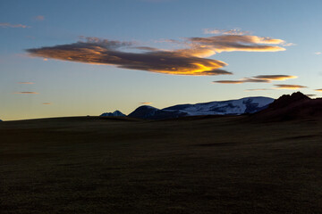 Majestic landscape featuring rolling hills under a vibrant sunset sky with unique cloud formations,...