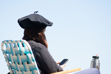 Country Woman with Beret Holding a Mate Thermos and Looking at Her Cell Phone